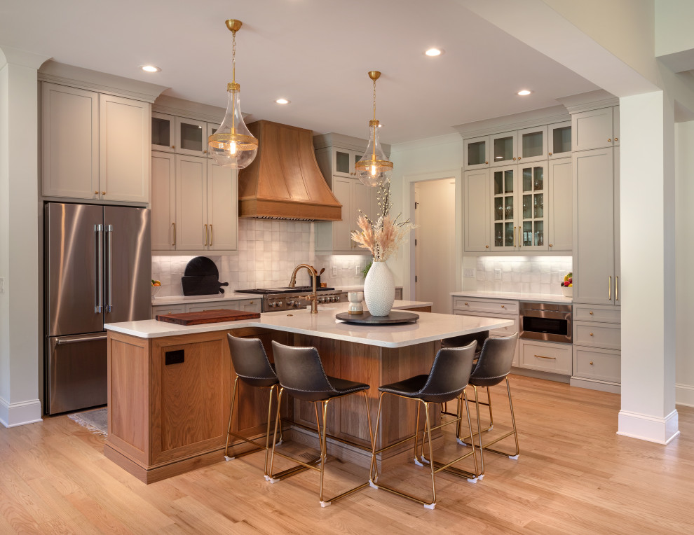 Design ideas for a large country eat-in kitchen in Atlanta with a farmhouse sink, shaker cabinets, grey cabinets, quartz benchtops, white splashback, ceramic splashback, stainless steel appliances, light hardwood floors, with island, brown floor and white benchtop.