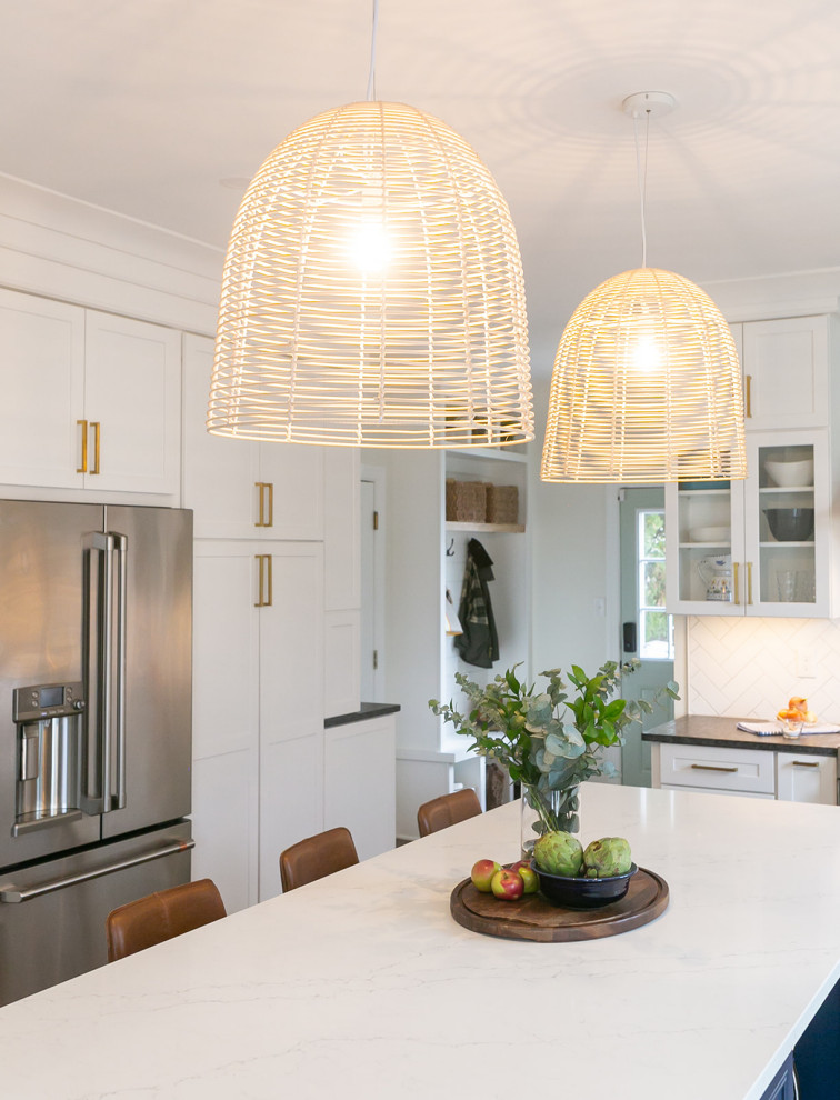 Large transitional l-shaped brown floor kitchen pantry photo in Baltimore with a drop-in sink, shaker cabinets, white cabinets, quartz countertops, white backsplash, ceramic backsplash, stainless steel appliances, an island and white countertops