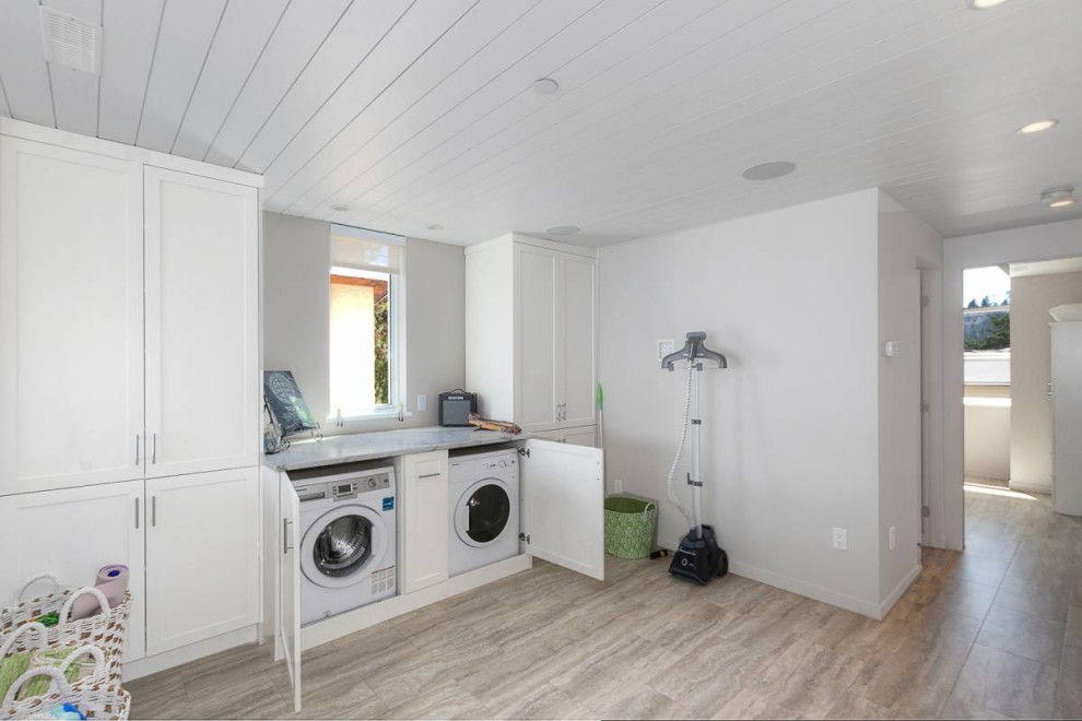 Inspiration for a small beach style single-wall laundry cupboard in Other with shaker cabinets, white cabinets, quartzite benchtops, white walls, vinyl floors, a concealed washer and dryer, grey floor, white benchtop and timber.