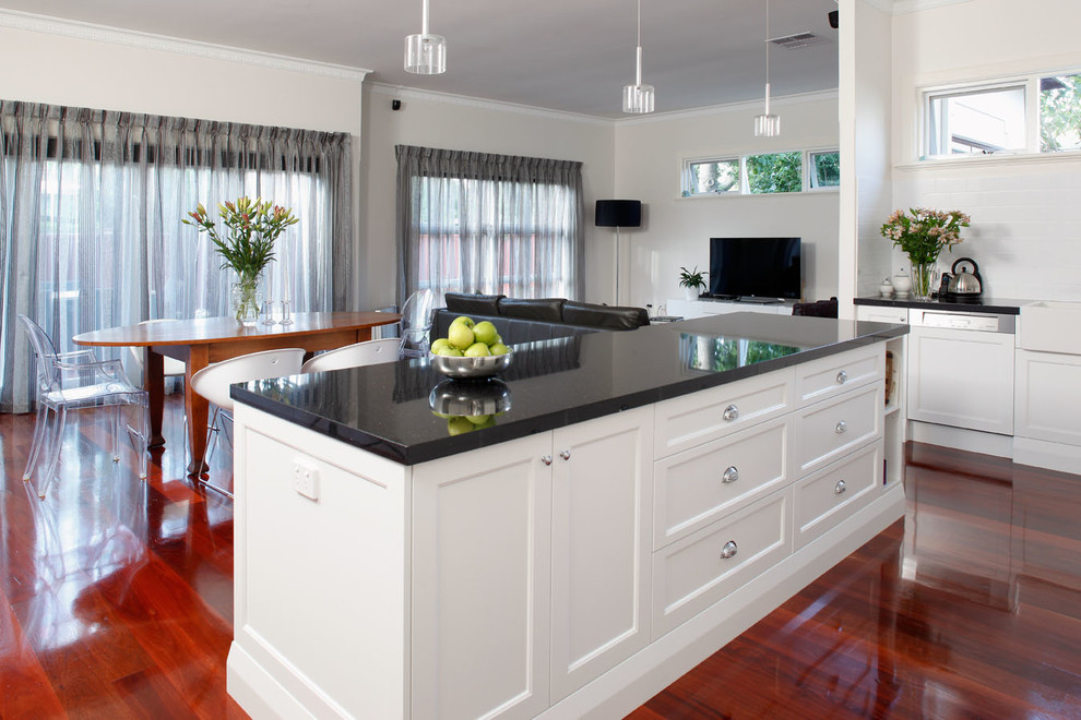 Design ideas for a mid-sized modern l-shaped eat-in kitchen in Perth with a farmhouse sink, flat-panel cabinets, white cabinets, granite benchtops, white splashback, glass sheet splashback, stainless steel appliances, dark hardwood floors and with island.