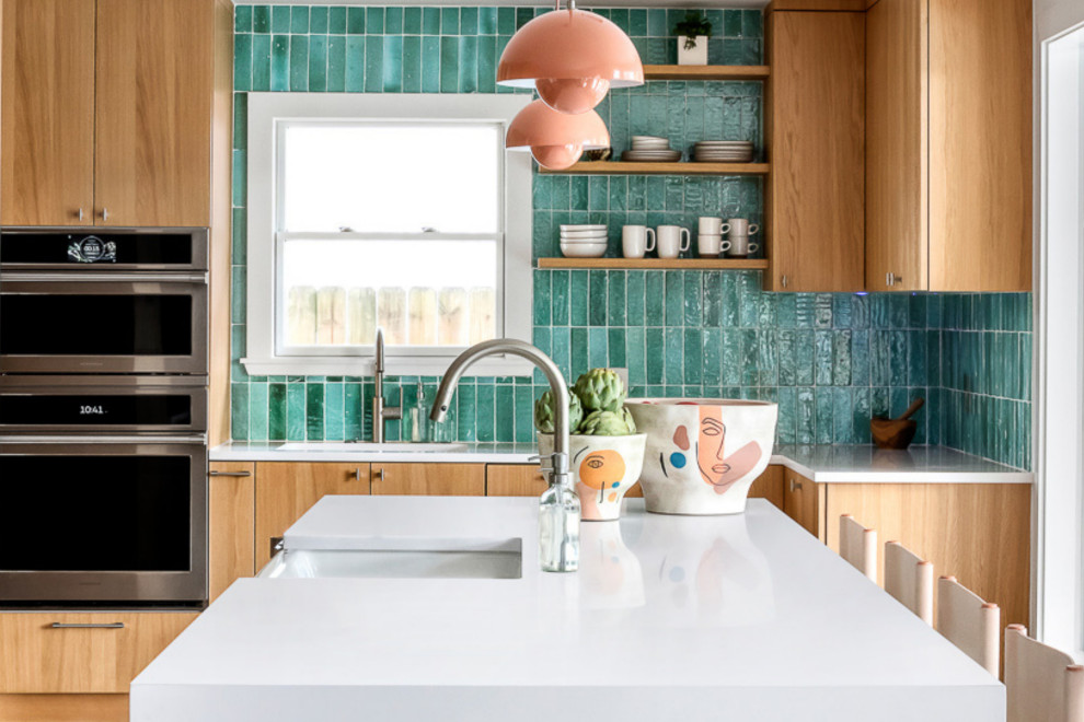 Small modern l-shaped kitchen/diner in Austin with a built-in sink, flat-panel cabinets, medium wood cabinets, glass worktops, blue splashback, ceramic splashback, integrated appliances, light hardwood flooring, an island, brown floors, white worktops and a drop ceiling.