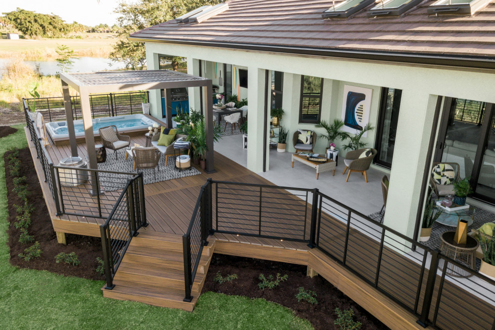 This is an example of a tropical backyard and ground level deck in Miami with an outdoor kitchen, a pergola and metal railing.