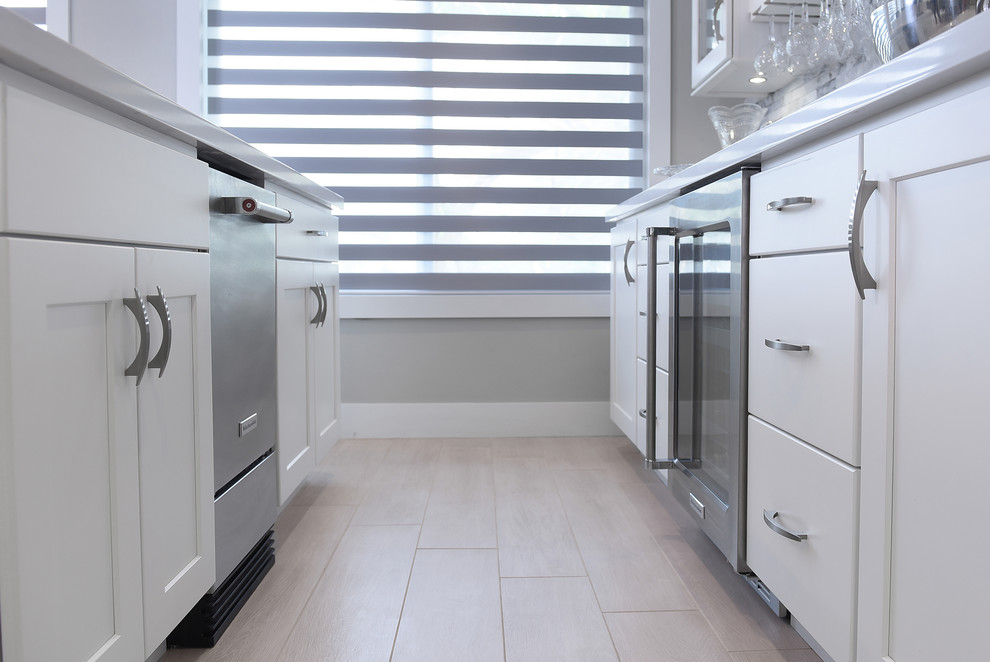 Inspiration for a large transitional l-shaped porcelain tile and gray floor open concept kitchen remodel in Miami with a farmhouse sink, shaker cabinets, gray cabinets, quartz countertops, gray backsplash, marble backsplash, stainless steel appliances and two islands