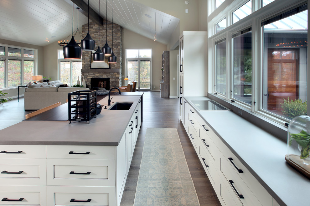 This is an example of a contemporary l-shaped open plan kitchen in Grand Rapids with shaker cabinets, white cabinets, concrete benchtops, medium hardwood floors and with island.