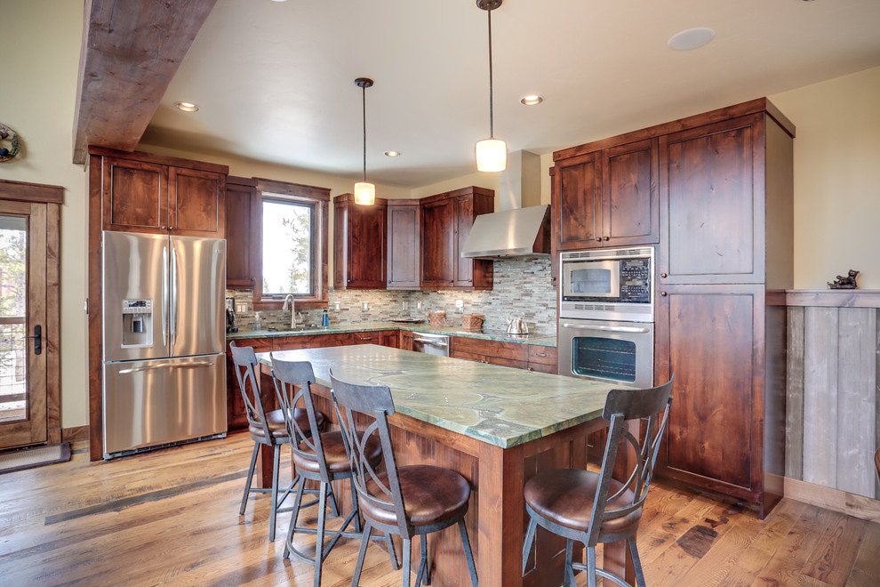 Photo of a large country l-shaped open plan kitchen in Denver with an undermount sink, shaker cabinets, medium wood cabinets, granite benchtops, multi-coloured splashback, matchstick tile splashback, stainless steel appliances, medium hardwood floors and with island.