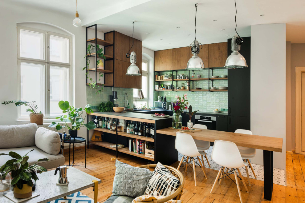 This is an example of a small open plan kitchen in Berlin with a double-bowl sink, flat-panel cabinets, light wood cabinets, green splashback, ceramic splashback, black appliances, porcelain floors, a peninsula, multi-coloured floor and grey benchtop.
