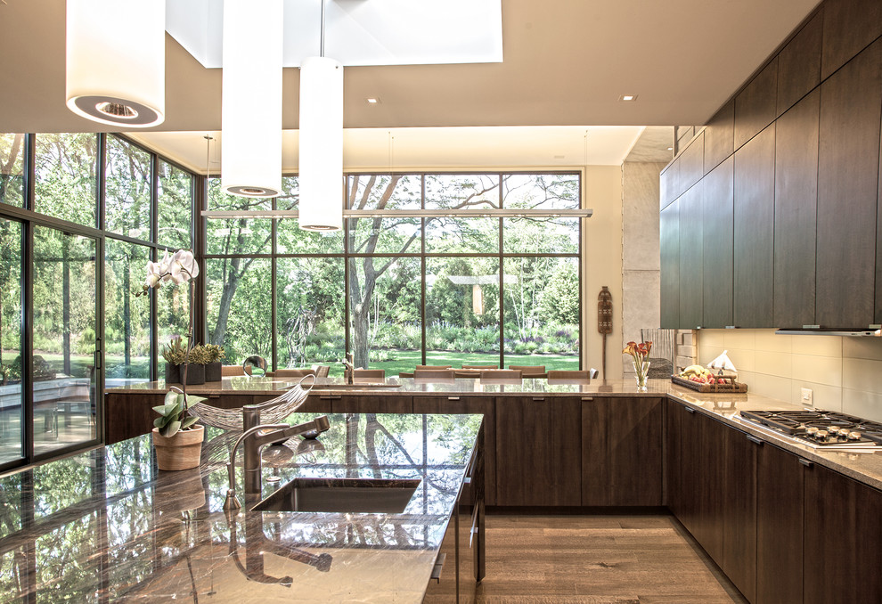 Example of a large trendy u-shaped medium tone wood floor and brown floor eat-in kitchen design in Chicago with a single-bowl sink, flat-panel cabinets, dark wood cabinets, glass countertops, beige backsplash, glass tile backsplash, stainless steel appliances and an island