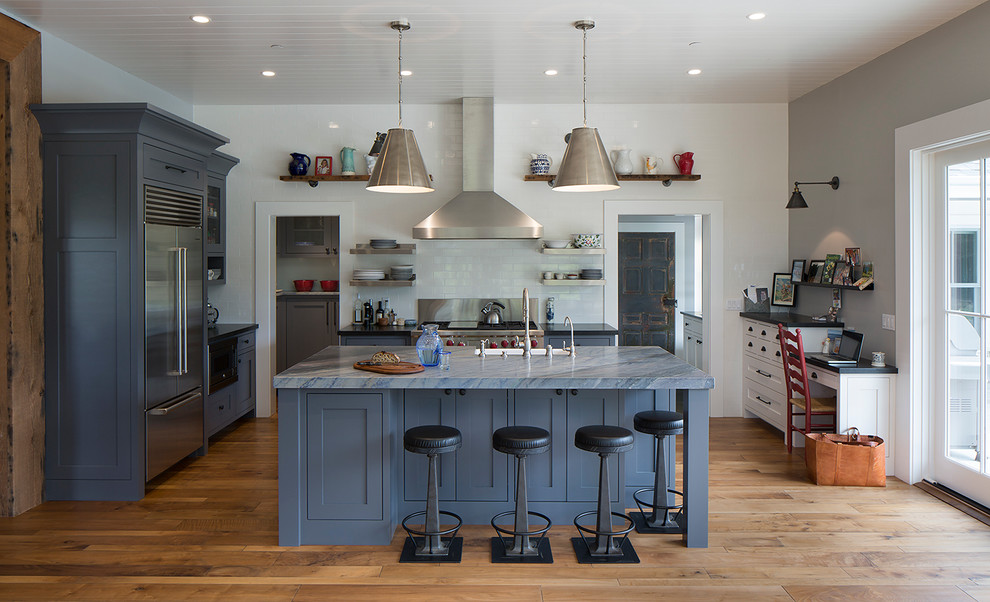 Country l-shaped kitchen in San Francisco with shaker cabinets, blue cabinets, white splashback, subway tile splashback, stainless steel appliances, medium hardwood floors, with island and blue benchtop.