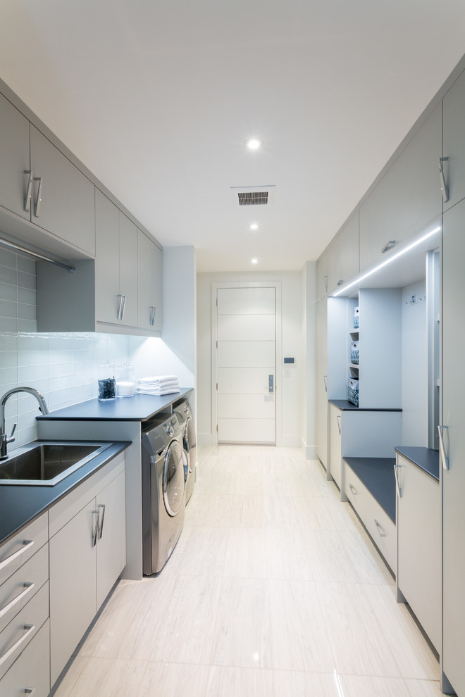 Inspiration for a contemporary galley utility room in Toronto with a drop-in sink, flat-panel cabinets, a side-by-side washer and dryer, grey benchtop and grey cabinets.