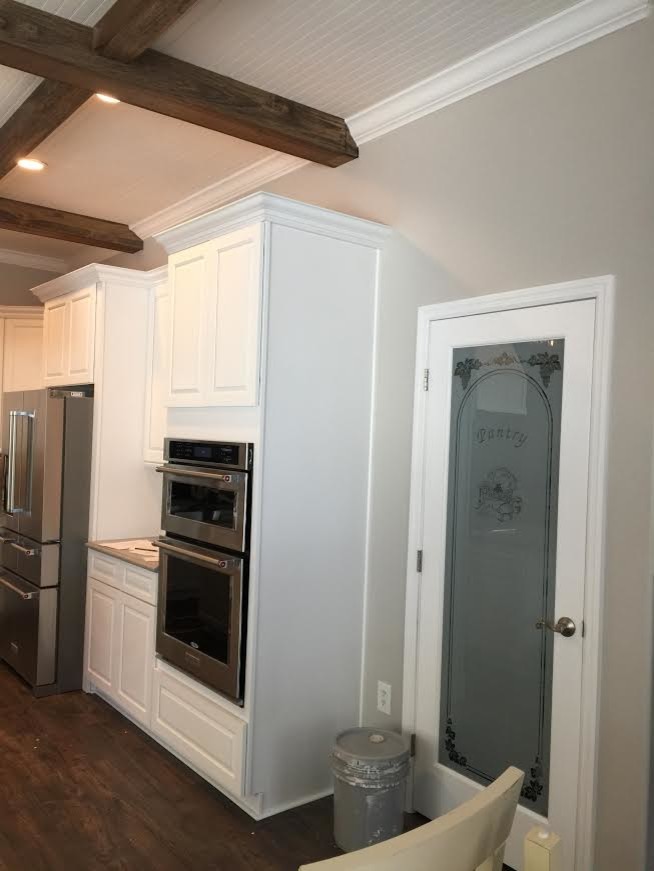 Inspiration for a large transitional l-shaped dark wood floor and brown floor enclosed kitchen remodel in Tampa with raised-panel cabinets, white cabinets, stainless steel appliances and an island