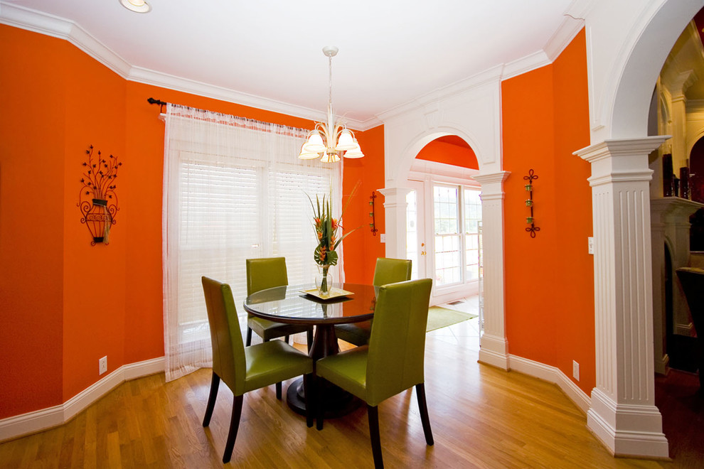 This is an example of an eclectic dining room in Other with orange walls and medium hardwood floors.