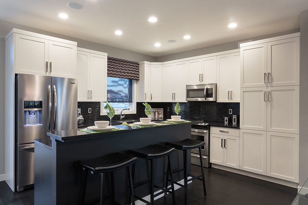 Kitchen - transitional dark wood floor kitchen idea with white cabinets, black backsplash, stainless steel appliances and an island