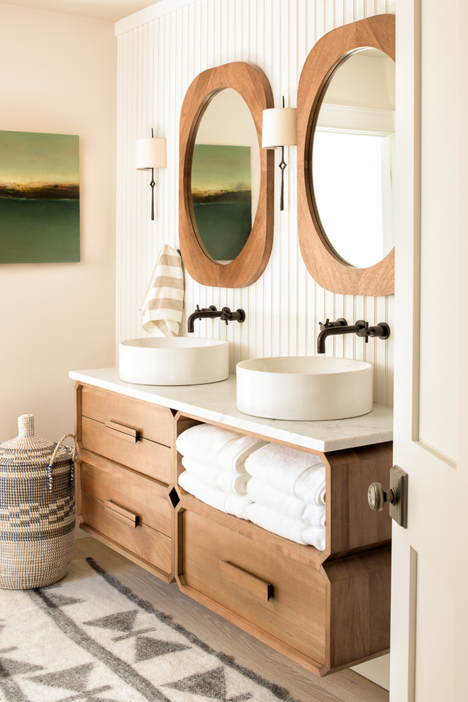 This is an example of a beach style bathroom in Portland Maine with medium wood cabinets, beige walls, light hardwood floors, a vessel sink and beige floor.