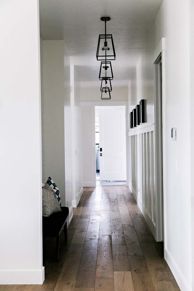 Photo of a mid-sized country hallway in Salt Lake City with white walls, medium hardwood floors and brown floor.