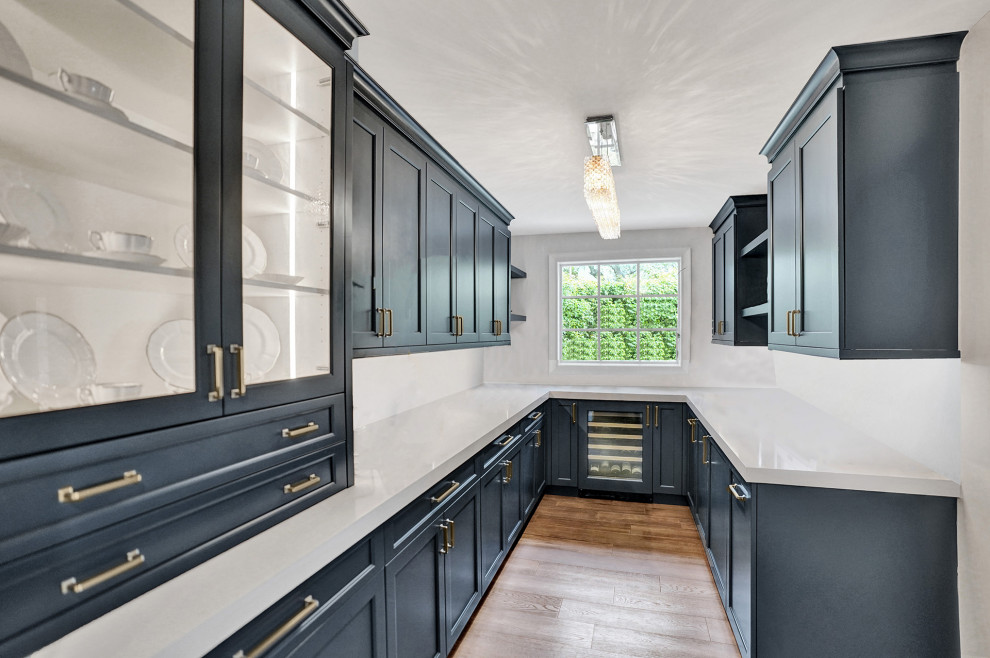 Example of a transitional kitchen pantry design in Miami with shaker cabinets, white cabinets, white backsplash, an island and white countertops