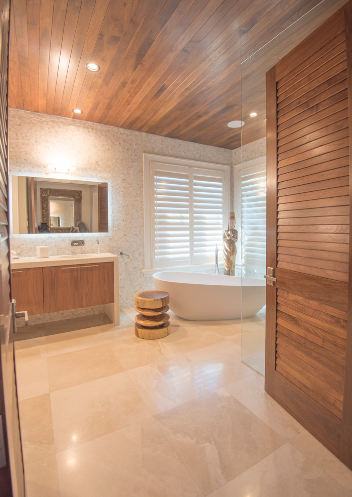 This is an example of a large tropical master bathroom in Tampa with flat-panel cabinets, medium wood cabinets, engineered quartz benchtops, a freestanding tub, an open shower, gray tile and stone tile.