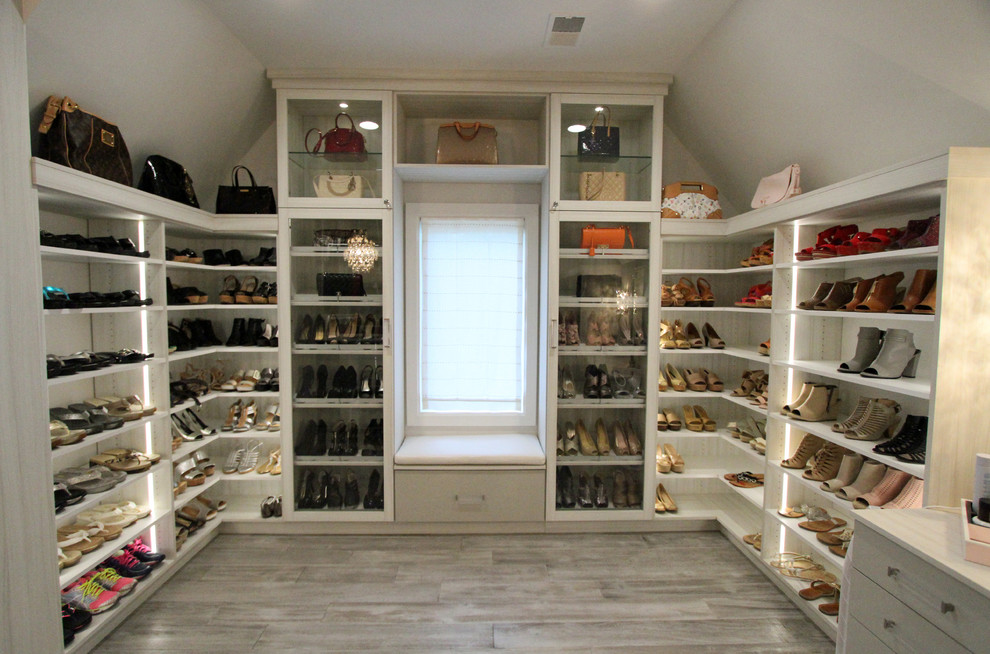 Photo of a large transitional women's walk-in wardrobe in Detroit with glass-front cabinets, light wood cabinets, light hardwood floors and grey floor.