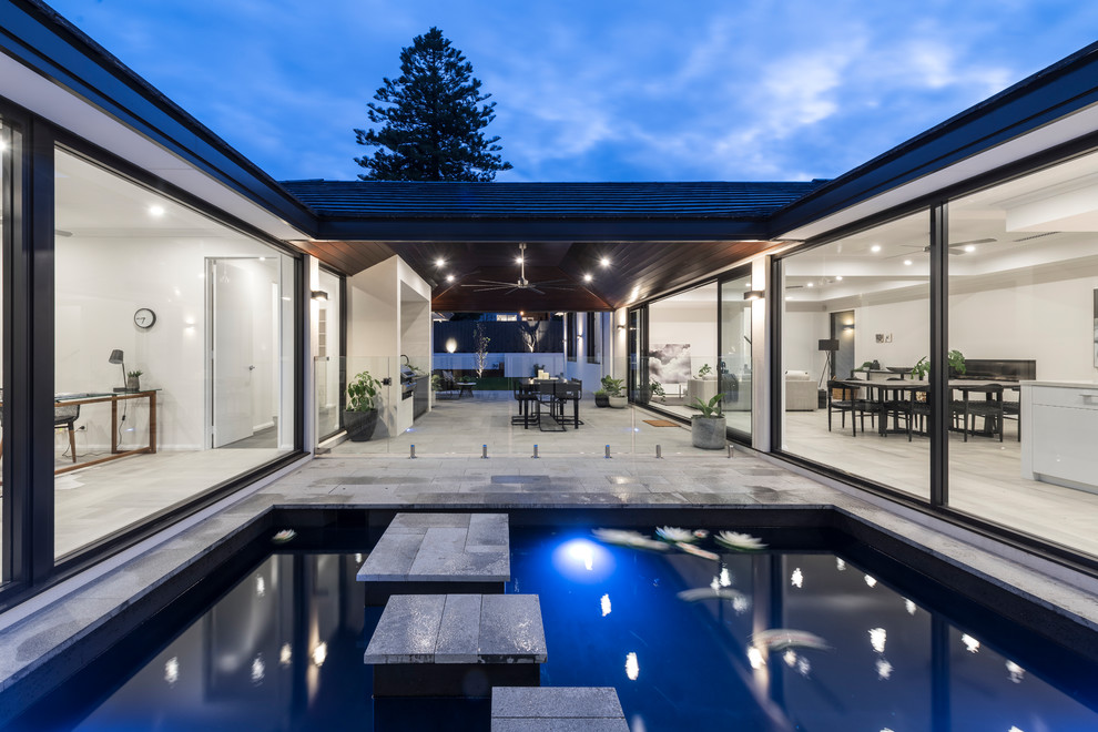 Large contemporary courtyard pool in Perth with natural stone pavers.
