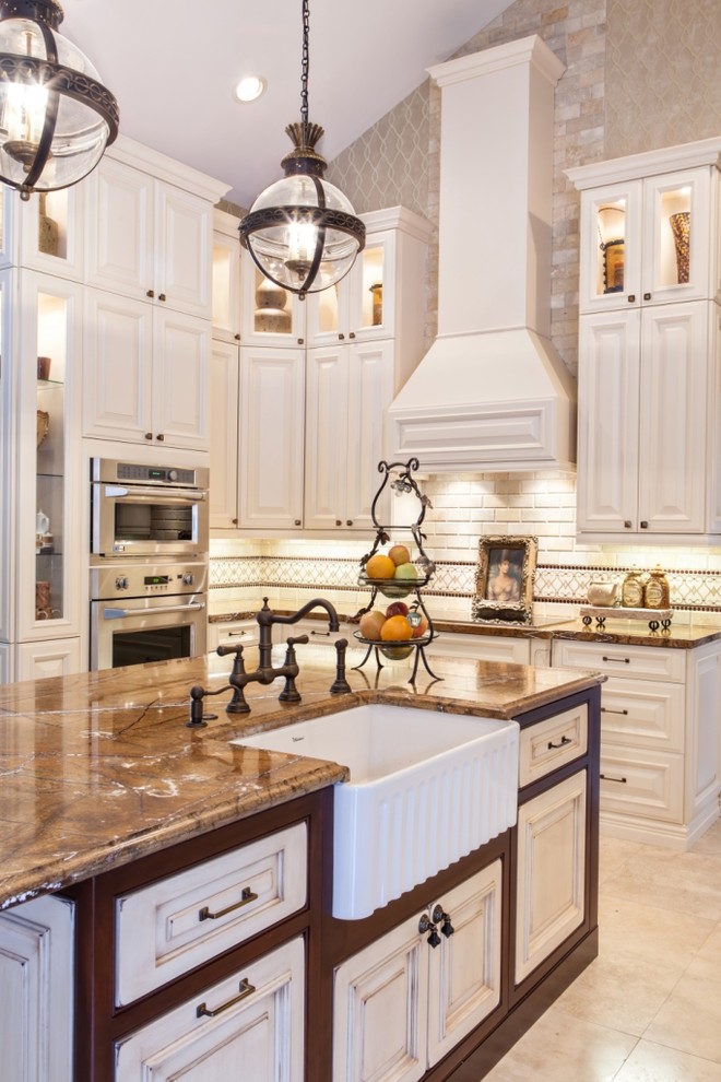 This is an example of a traditional kitchen in Miami with a farmhouse sink, raised-panel cabinets, white cabinets, beige splashback, subway tile splashback and stainless steel appliances.