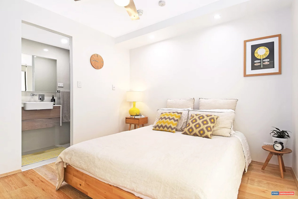 Cette photo montre une petite chambre parentale scandinave avec un mur blanc, parquet clair et un sol beige.
