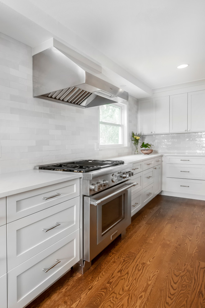 Inspiration for a transitional dark wood floor and brown floor kitchen remodel in Denver with raised-panel cabinets, white cabinets, multicolored backsplash, subway tile backsplash, stainless steel appliances and white countertops