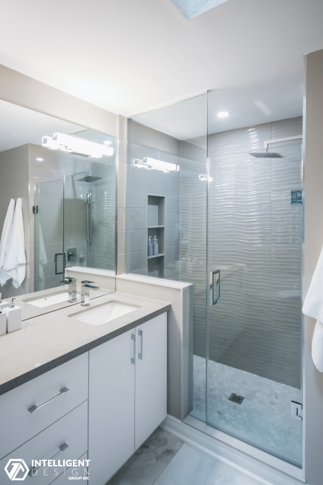 Large trendy master beige tile and limestone tile limestone floor, beige floor and double-sink corner bathtub photo in Toronto with flat-panel cabinets, white cabinets, a one-piece toilet, brown walls, an undermount sink, quartz countertops, a hinged shower door, beige countertops, a niche and a freestanding vanity