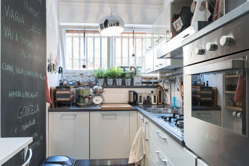 Small contemporary l-shaped kitchen in Rome with white cabinets, stainless steel appliances, no island, a drop-in sink, flat-panel cabinets, white splashback and ceramic splashback.