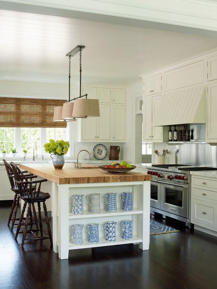 Kitchen pantry - large l-shaped kitchen pantry idea in New York with a double-bowl sink, beaded inset cabinets, white cabinets, wood countertops, white backsplash, stainless steel appliances and an island