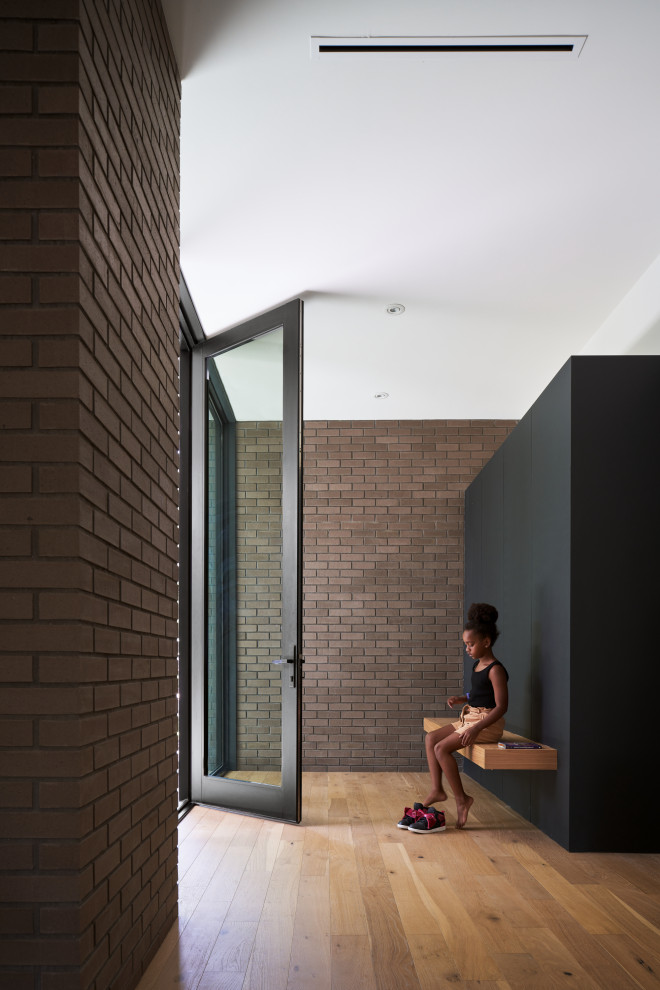 Ejemplo de distribuidor minimalista con paredes marrones, suelo de madera en tonos medios, puerta metalizada y suelo marrón