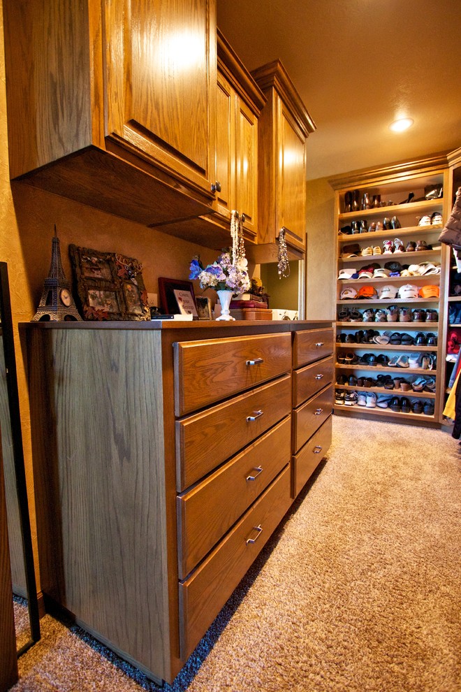 Design ideas for a large gender-neutral walk-in wardrobe in Other with raised-panel cabinets, dark wood cabinets and carpet.