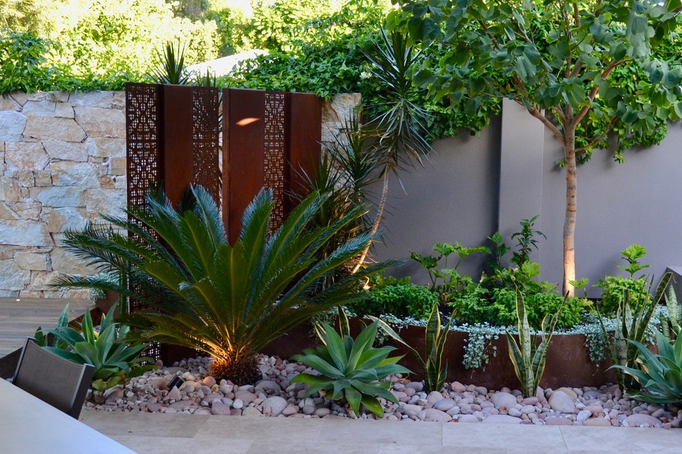 This is an example of a small contemporary backyard partial sun xeriscape for summer in Perth with natural stone pavers and with raised garden bed.