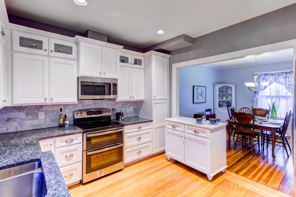 Eat-in kitchen - large u-shaped medium tone wood floor eat-in kitchen idea in Providence with an undermount sink, shaker cabinets, white cabinets, granite countertops, blue backsplash, stone tile backsplash, stainless steel appliances and an island