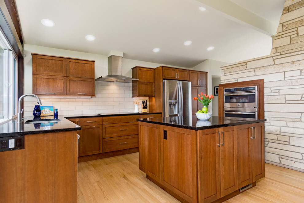 Inspiration for a mid-sized arts and crafts l-shaped eat-in kitchen in Seattle with an undermount sink, flat-panel cabinets, medium wood cabinets, quartz benchtops, beige splashback, ceramic splashback, stainless steel appliances, light hardwood floors, with island and brown floor.