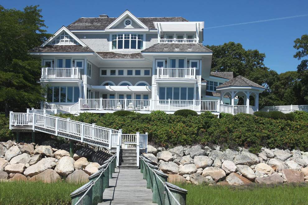 This is an example of a large beach style three-storey grey exterior in Orange County with wood siding and a hip roof.