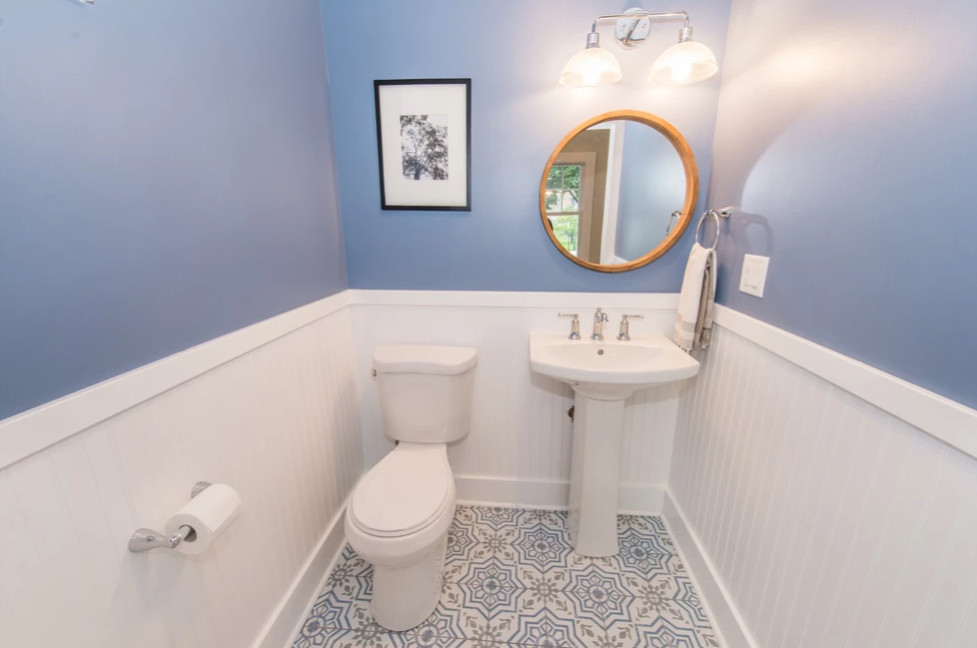 Photo of a mid-sized transitional bathroom in New York with white cabinets, a one-piece toilet, ceramic tile, blue walls, ceramic floors, a pedestal sink, multi-coloured floor, white benchtops, a single vanity and a freestanding vanity.