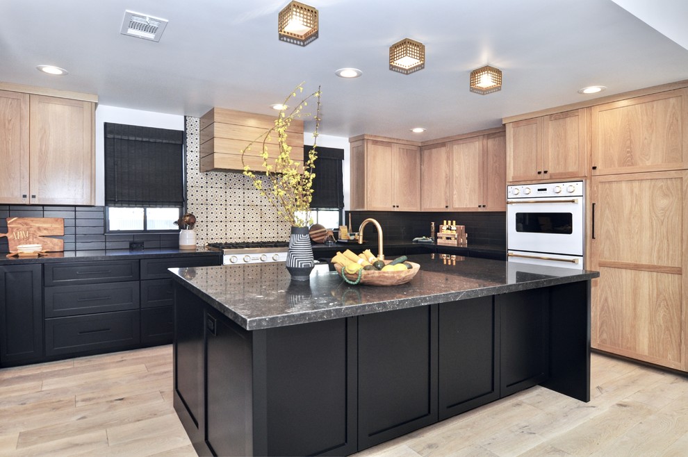 Inspiration for a large transitional u-shaped light wood floor and beige floor eat-in kitchen remodel in Orange County with a single-bowl sink, shaker cabinets, light wood cabinets, marble countertops, black backsplash, cement tile backsplash, white appliances, an island and black countertops