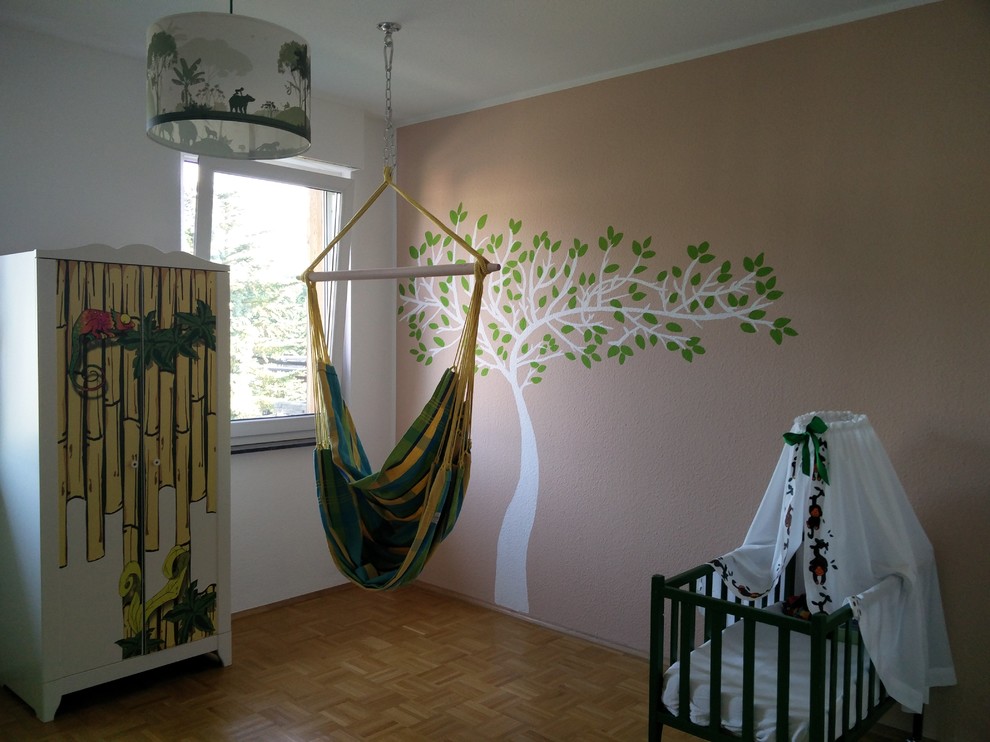 Design ideas for a mid-sized traditional gender-neutral nursery in Dusseldorf with beige walls and light hardwood floors.
