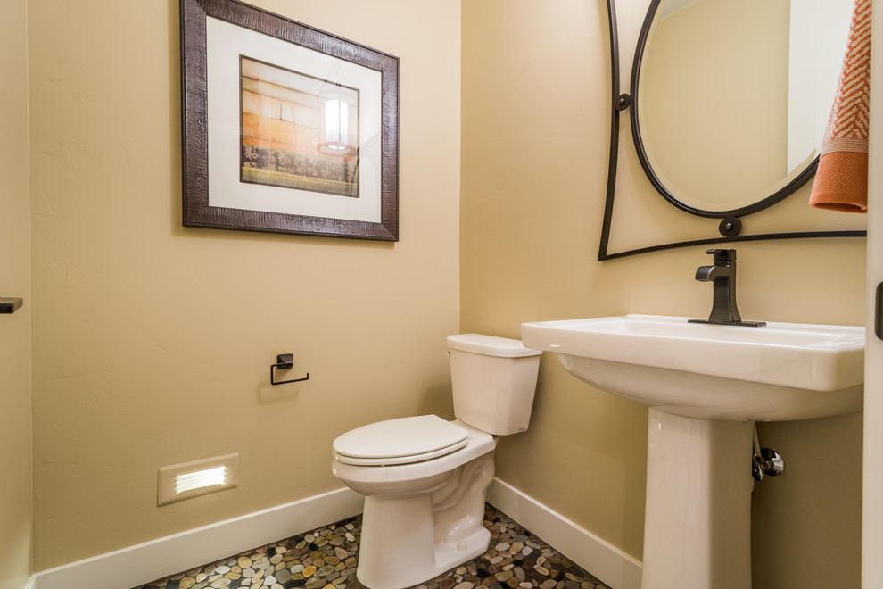 Photo of a small transitional powder room in Salt Lake City with a two-piece toilet, beige walls, pebble tile floors and a pedestal sink.