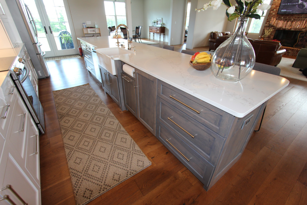 Mid-sized transitional u-shaped dark wood floor and brown floor enclosed kitchen photo in St Louis with an undermount sink, shaker cabinets, white cabinets, quartz countertops, white backsplash, ceramic backsplash, stainless steel appliances, an island and white countertops