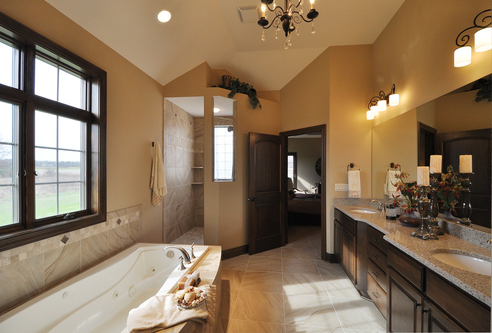 Inspiration for a large traditional master bathroom in Milwaukee with an undermount sink, raised-panel cabinets, dark wood cabinets, granite benchtops, a hot tub, a corner shower, beige tile, ceramic tile, beige walls and ceramic floors.