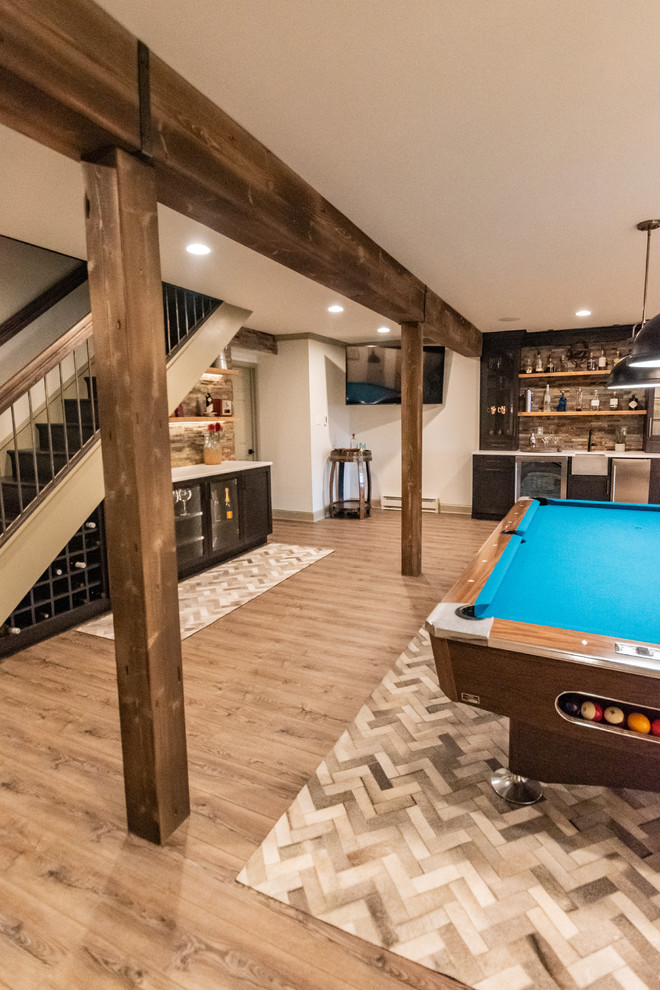 Inspiration for a large country walk-out basement in Philadelphia with white walls, laminate floors, a corner fireplace, a stone fireplace surround and brown floor.