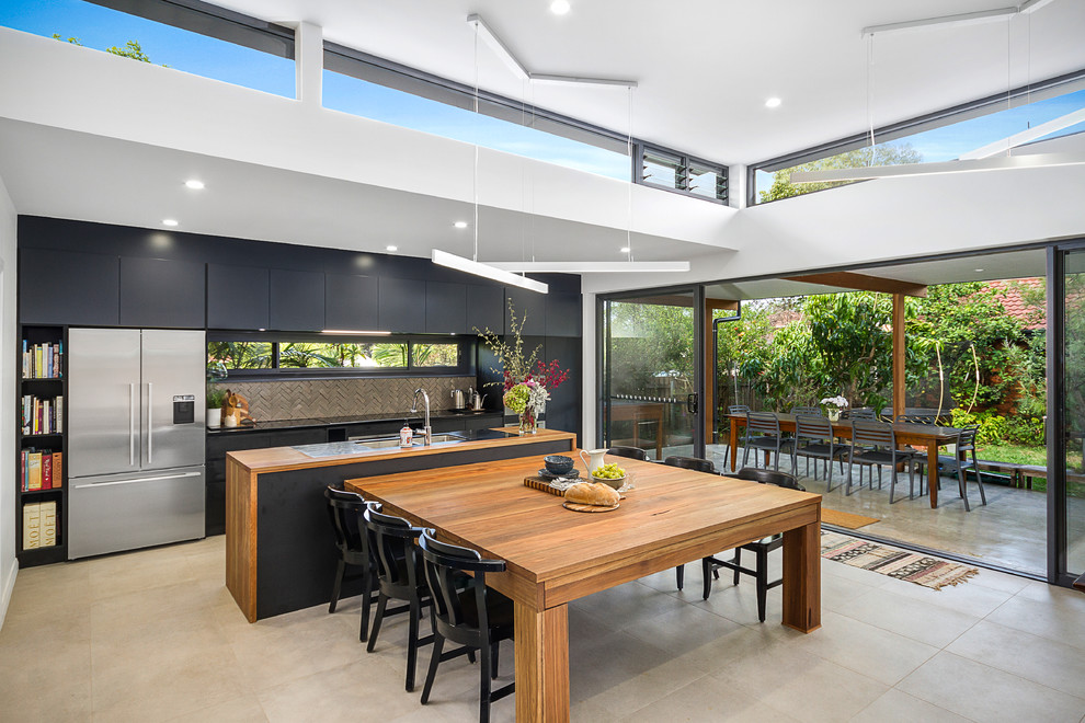 Inspiration for a contemporary galley eat-in kitchen in Sydney with flat-panel cabinets, black cabinets, wood benchtops, grey splashback, stainless steel appliances, with island, beige floor and brown benchtop.