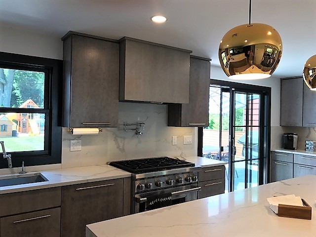This is an example of a contemporary open plan kitchen in New York with grey cabinets, marble benchtops, white splashback, marble splashback, stainless steel appliances and with island.