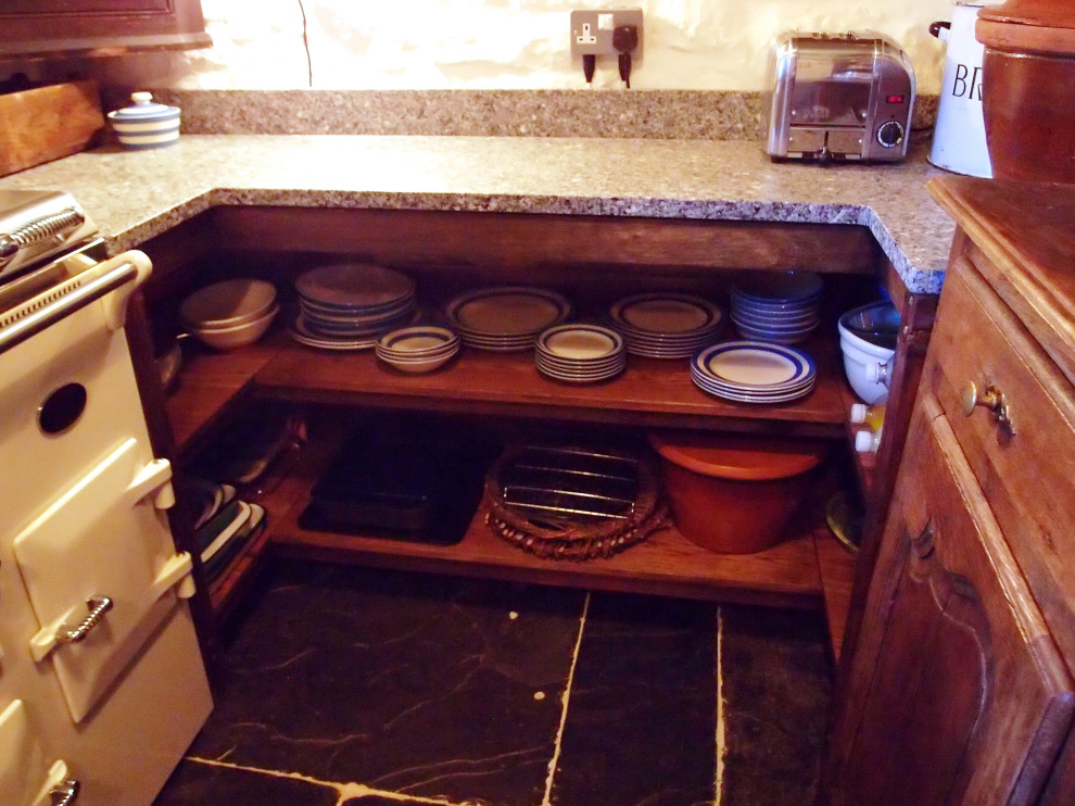 Foto på ett avskilt, litet rustikt grå u-kök, med en rustik diskho, skåp i shakerstil, skåp i mörkt trä, granitbänkskiva, vita vitvaror, skiffergolv och grått golv