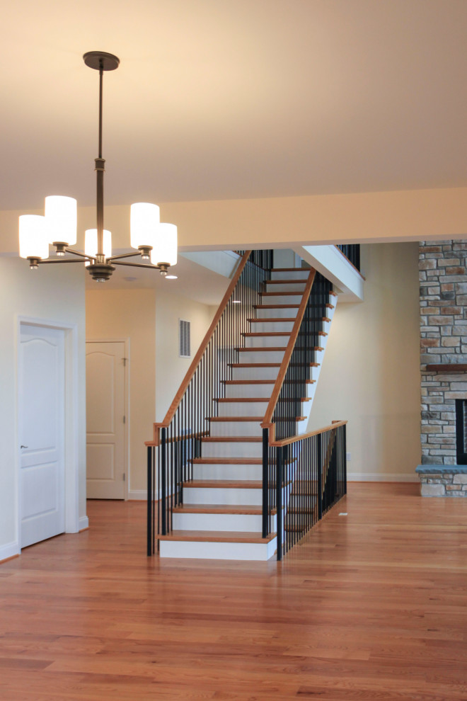 Photo of a large traditional wood floating mixed railing staircase in DC Metro with wood risers and tongue and groove walls.