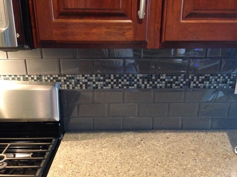 Kitchen - transitional kitchen idea in Chicago with raised-panel cabinets, dark wood cabinets, quartz countertops, gray backsplash and subway tile backsplash