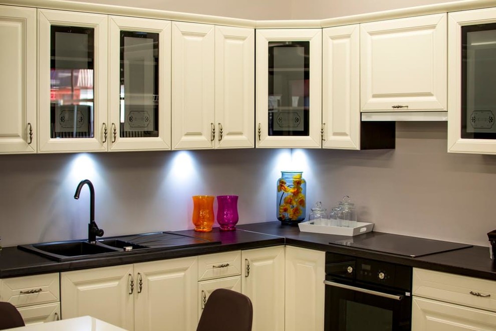 Inspiration for a mid-sized transitional u-shaped enclosed kitchen remodel in Orlando with a drop-in sink, raised-panel cabinets, white cabinets, granite countertops, gray backsplash, black appliances and an island