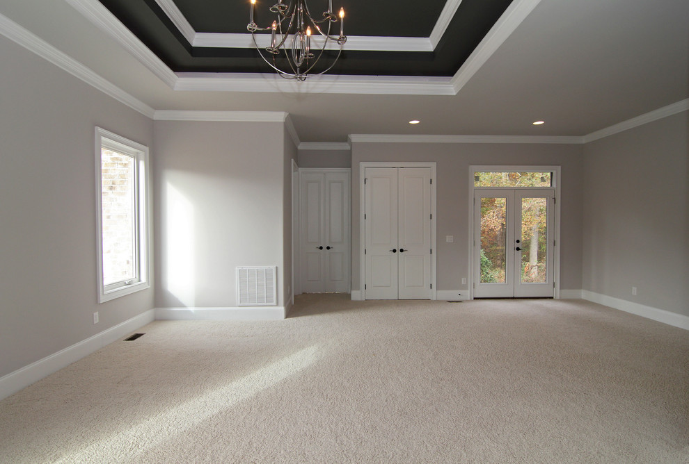 Expansive traditional master bedroom in Raleigh with grey walls and carpet.