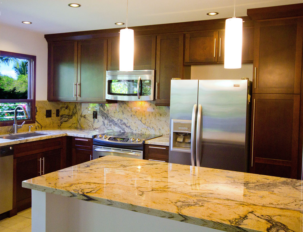 This is an example of a mid-sized tropical u-shaped eat-in kitchen in Hawaii with a double-bowl sink, shaker cabinets, medium wood cabinets, granite benchtops, stainless steel appliances and a peninsula.
