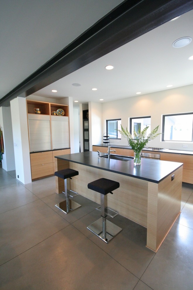 Large modern galley eat-in kitchen in Grand Rapids with an undermount sink, flat-panel cabinets, light wood cabinets, solid surface benchtops, stainless steel appliances, concrete floors and with island.